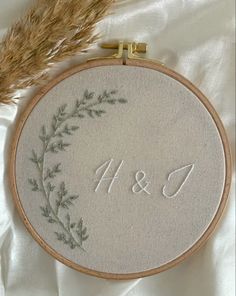 a close up of a embroidery on a white cloth with a gold needle and some brown grass