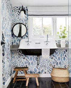 a bathroom with blue and white wallpaper, black flooring and a wooden stool