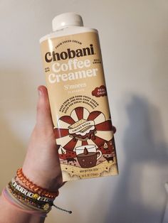 a person holding up a bottle of coffee creamer in their left hand and bracelets on the wrist