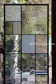 a glass window with many different colors and patterns on it's side, reflecting the trees outside