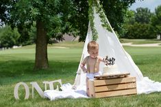 a small child standing in front of a teepee with a cake on it's chest