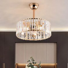 a chandelier hanging from the ceiling above a dining room table with flowers on it