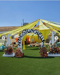 an outdoor area with flowers and decorations on the grass, under a yellow awning