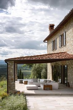 an outdoor living area with couches and tables in front of a large stone building