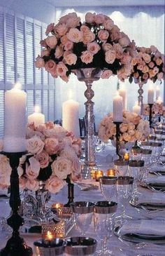 a long table is set with candles and flowers in centerpieces for an elegant dinner