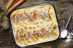 a casserole in a baking dish with powdered sugar on top and carrots next to it