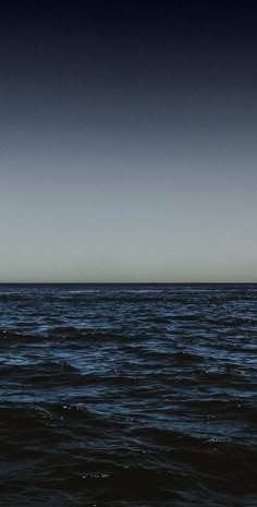 an airplane is flying over the ocean on a clear day with dark blue skies above