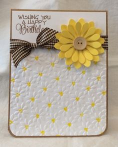 a white card with yellow flowers and a button on the front that says wishing you a happy birthday