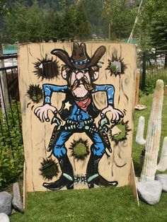 a wooden sign with an image of a cowboy on it in front of some cactuses