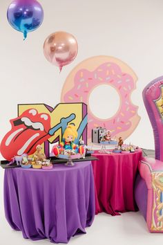 a pink chair sitting next to a table covered in donuts and other items on top of it