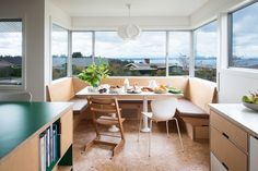 a kitchen with a table and chairs in front of large windows that overlook the ocean