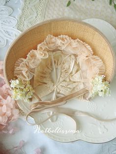 a white plate topped with a straw hat on top of a lace covered table cloth