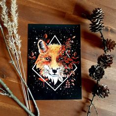 a card with an image of a fox on it next to pine cones and dried flowers