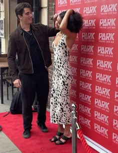 a man standing next to a woman on a red carpet in front of a wall