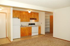 an empty kitchen with wooden cabinets and white appliances in it's center room area