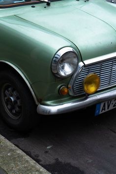 an old green car is parked on the street