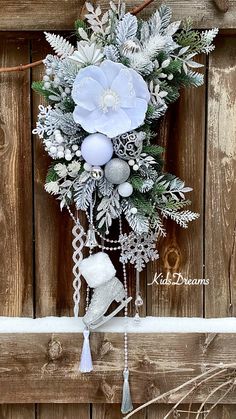 a christmas wreath hanging on the side of a wooden fence with snowflakes and ornaments