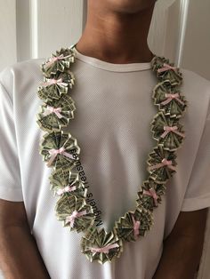 a man wearing a white t - shirt and pink ribbon necklace with dollar bills on it