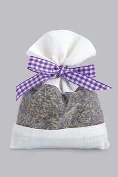 a bag filled with seeds and tied with a purple ribbon on the front, sitting on a gray background