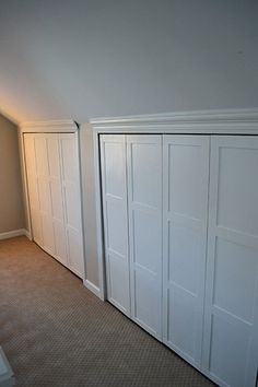 an empty room with white closet doors and carpet