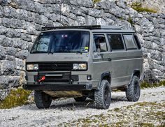 a grey van parked next to a stone wall