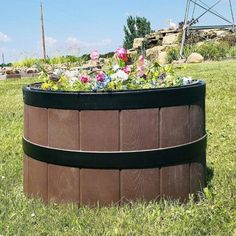 a large wooden barrel filled with flowers in the grass