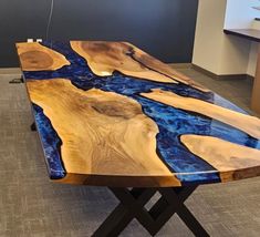 a table made out of wood with blue and black paint on the top, sitting in an office