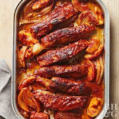 an image of chicken wings and onions in the baking pan on top of a wooden table