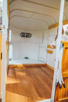 a woman standing in the doorway of a white truck with wood flooring and walls