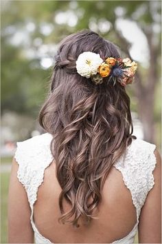 the back of a woman's head with long hair and flowers in her hair