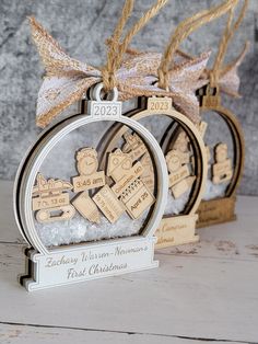 two wooden christmas ornaments hanging from twine with ribbon on top of each ornament