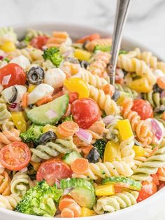 a pasta salad with broccoli, tomatoes, cucumbers and olives