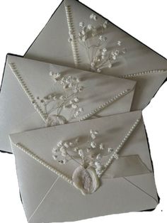 three envelopes with flowers and pearls on them