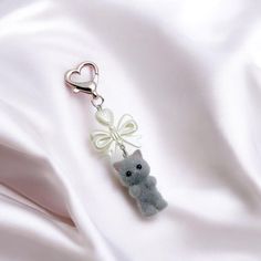 a keychain with a cat on it is laying on a white satin surface