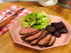 a plate with meat, lettuce and beets on it next to a fork