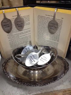 an open book with spoons in it on top of a metal dish filled with silverware