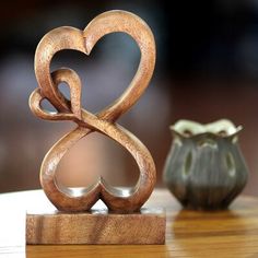 two wooden hearts are sitting on a table next to a small vase and an ornament