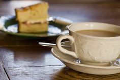 a cup of coffee sitting on top of a saucer next to a slice of cake