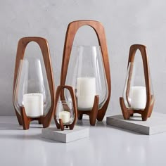 three wooden and glass vases with candles in them