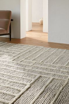 an area rug in the middle of a living room with a chair and couch behind it