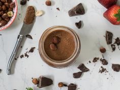 a jar filled with chocolate and nuts on top of a table next to other foods