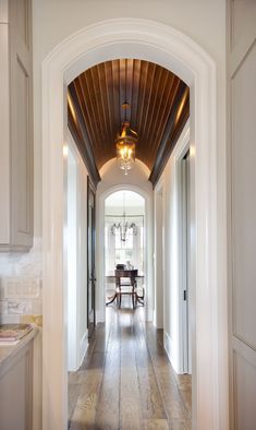 an archway leading to a dining room and kitchen area in a home with wood floors