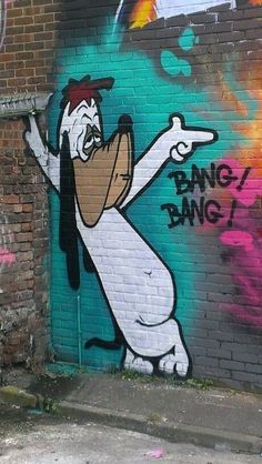 graffiti painted on the side of a brick building in an alleyway, depicting a cartoon character pointing at something