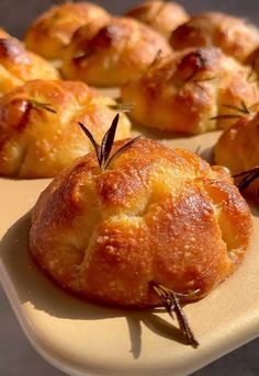 several small pastries on a white tray with rosemary sprigs in the middle