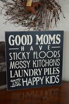 a sign that says good moms have sticky floors messy kitchens laundry piles and happy kids