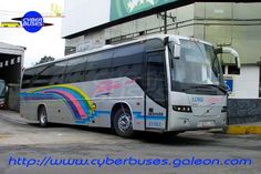 a silver bus parked in front of a building next to a parking lot with an advertisement on the side