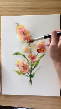 someone is painting flowers with watercolors on paper