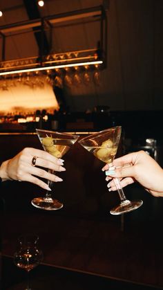 two women toasting with cocktails at a bar