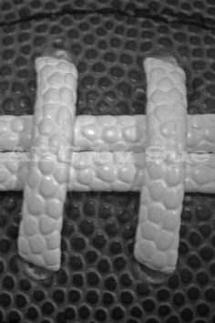 a close up of a football on a mesh surface with the letter t spelled out