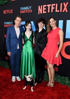 three people and a dog posing for a photo on the red carpet at netflix's family